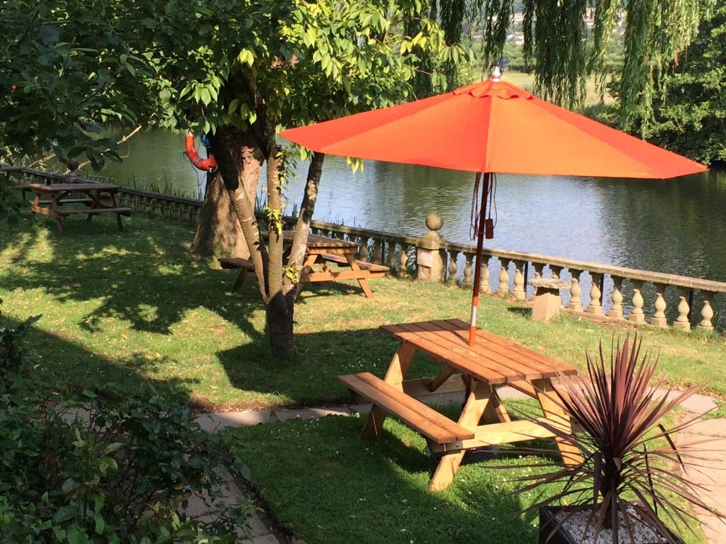 Picnic tables and orange umbrellas in the hotel garden by the Avon