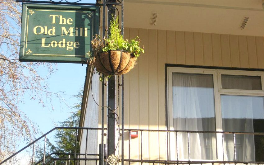 The Old Mill Lodge sign with hanging basket above the entrance